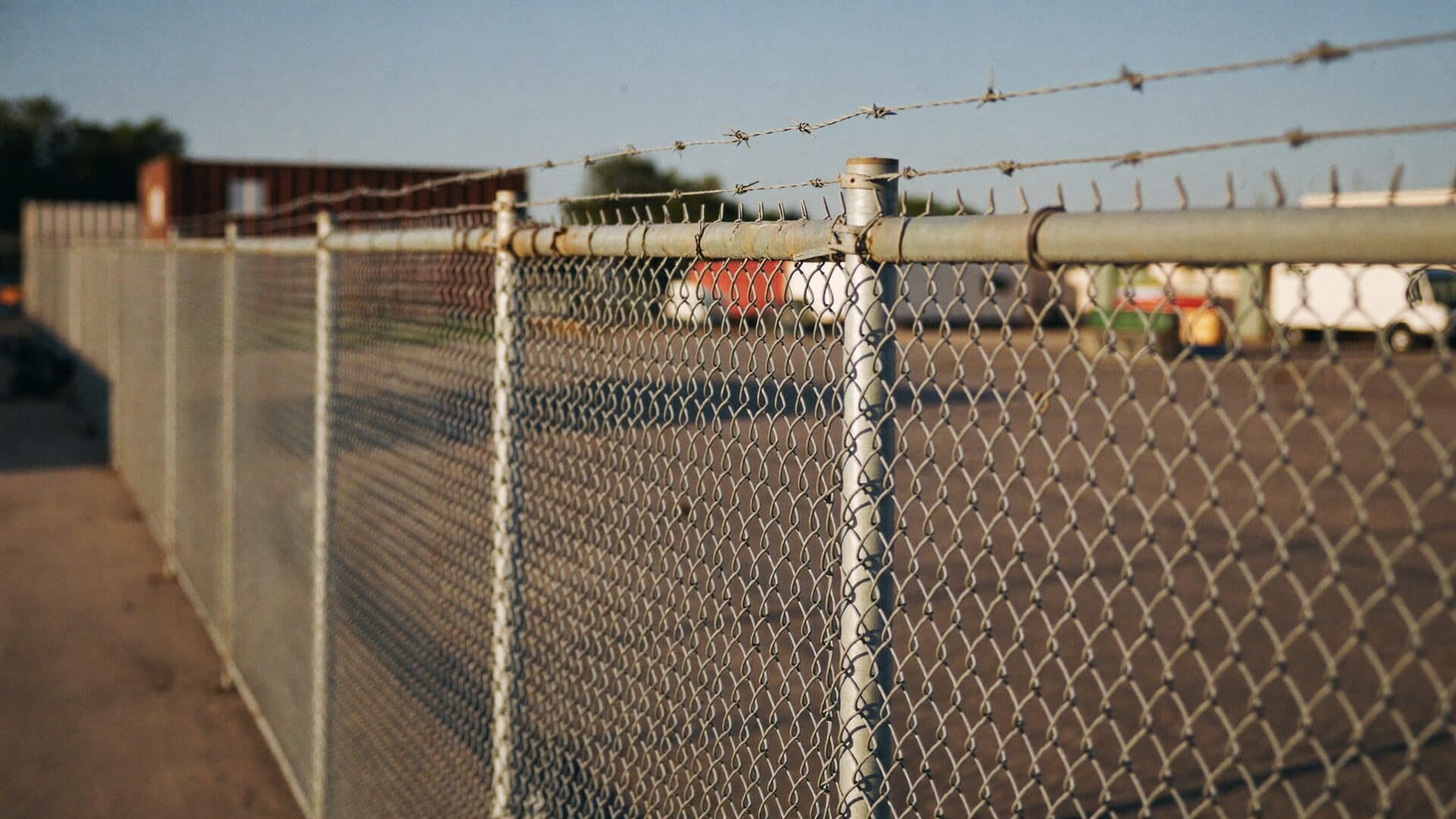 Commercial galvanized chain-link security fence with barbed wire at a Northeast Florida industrial yard